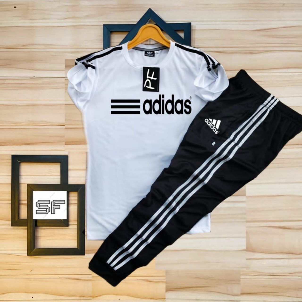 White Adidas t-shirt and black pants with white stripes on a wooden surface