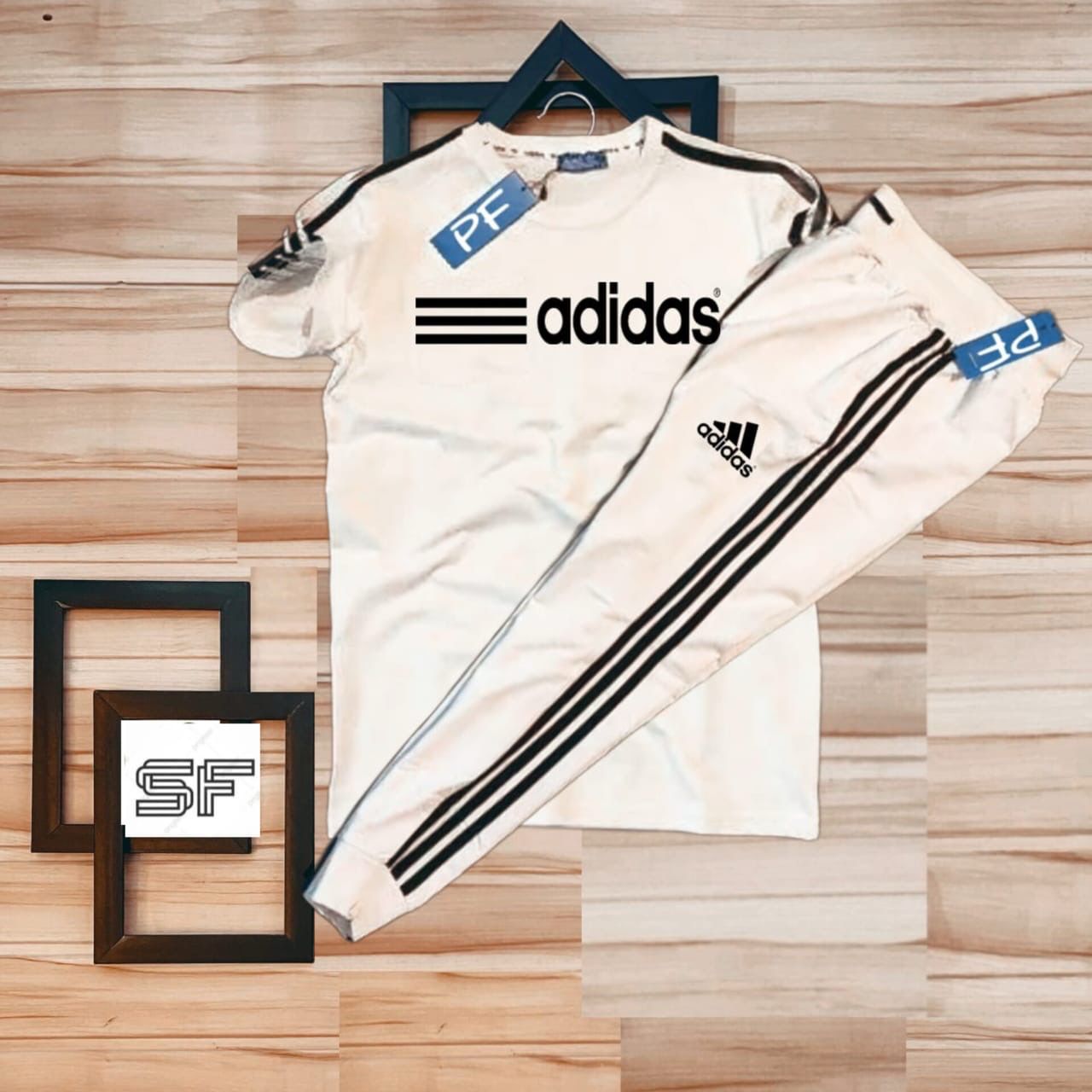 White Adidas tracksuit with black stripes on a wooden surface