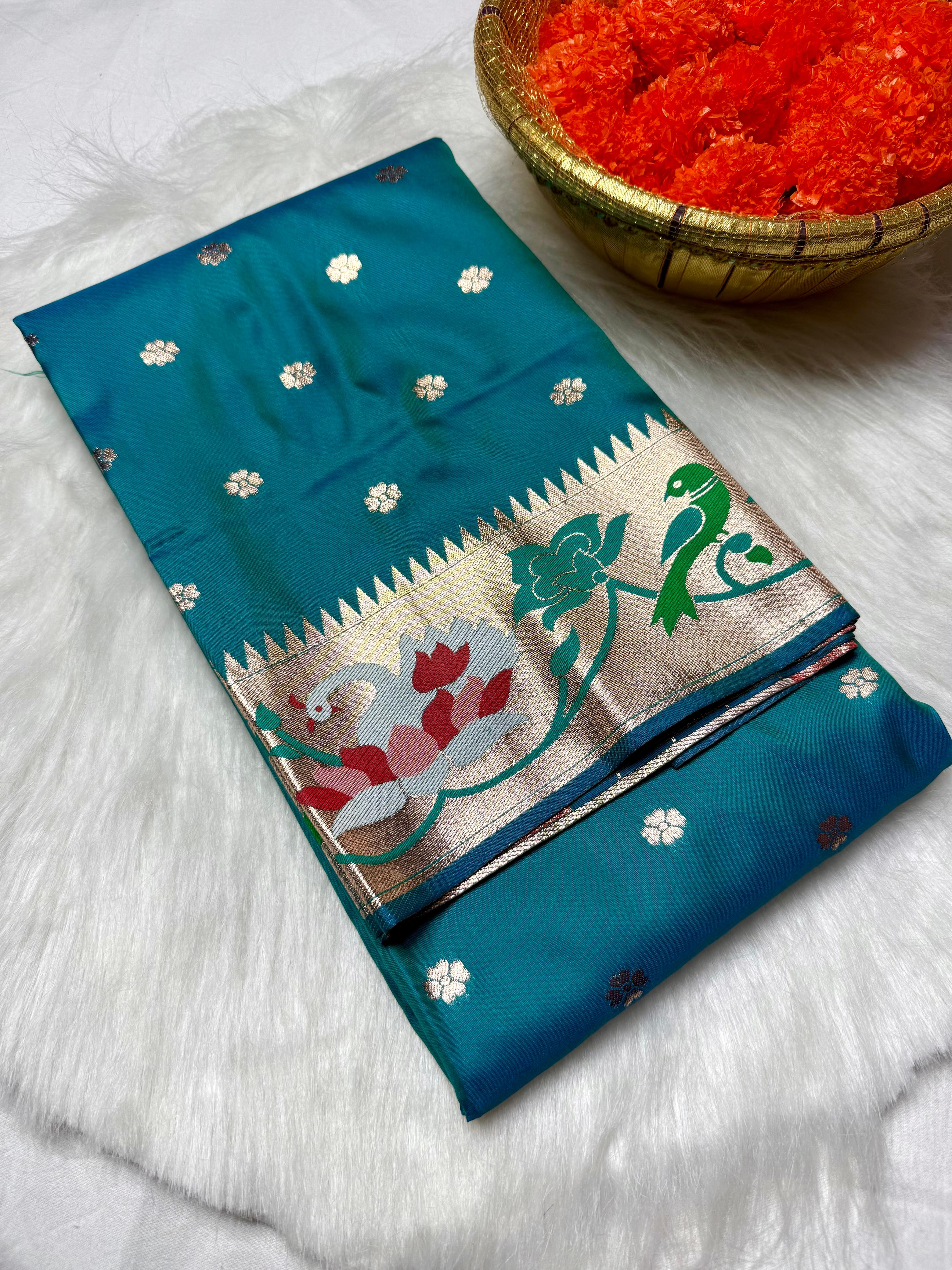 Experience timeless elegance with this Trending Rajhans Brocade Paithani Saree, crafted from premium pure soft silk. Designed with all-over traditional buttis and a luxurious 4/1 rich pallu, this saree reflects royal Maharashtrian craftsmanship. Comes with a matching running blouse piece, making it ideal for weddings, festive occasions, and traditional celebrations.