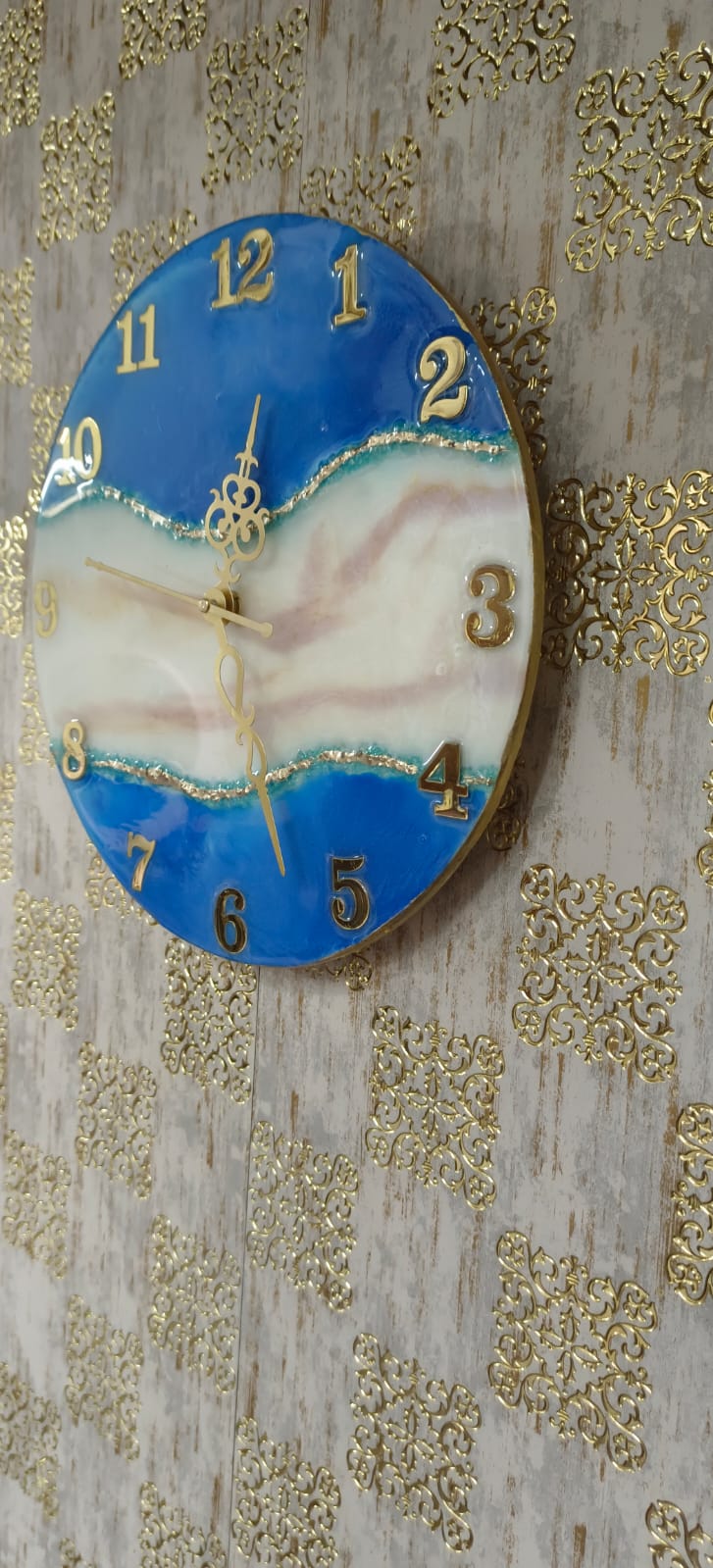 Add a touch of luxury and artistic elegance to your space with the NAVYA Handmade Resin Wall Clock. Expertly crafted using premium-quality resin, this designer clock showcases a mesmerizing marble and agate-inspired pattern with flowing teal, white, and subtle gold accents—making every piece truly one of a kind.