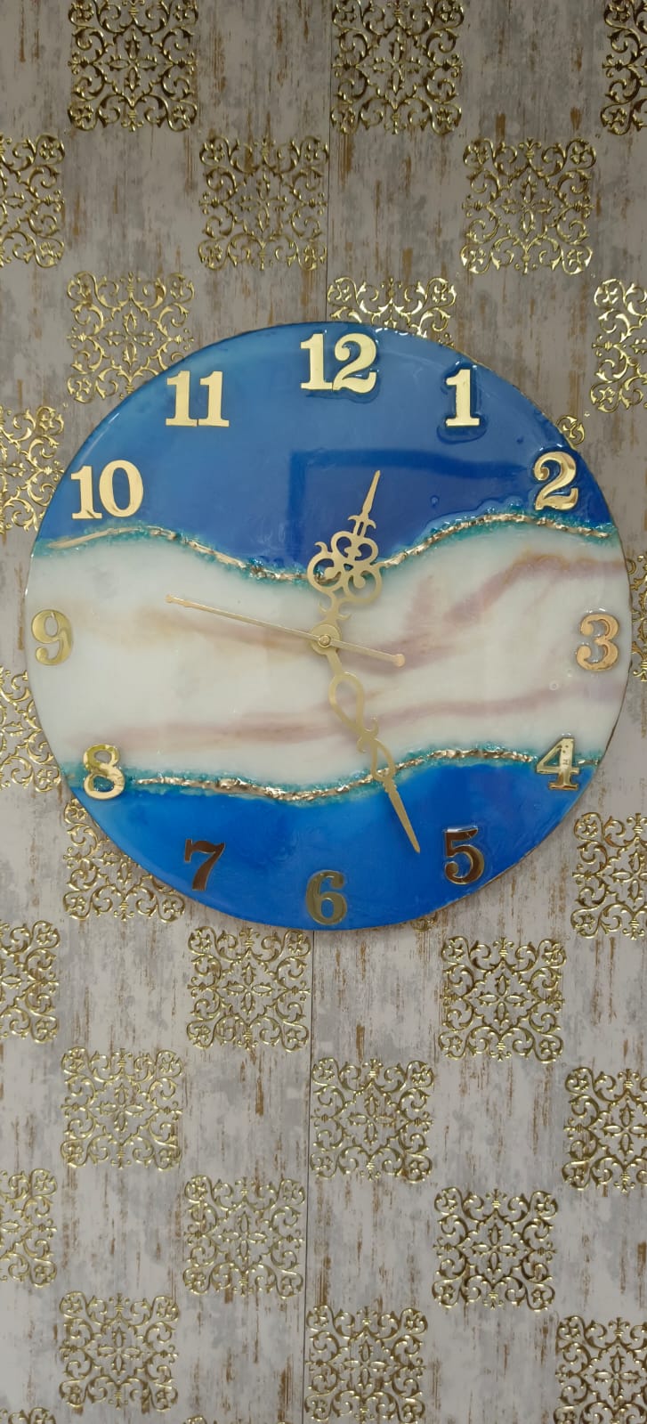 Add a touch of luxury and artistic elegance to your space with the NAVYA Handmade Resin Wall Clock. Expertly crafted using premium-quality resin, this designer clock showcases a mesmerizing marble and agate-inspired pattern with flowing teal, white, and subtle gold accents—making every piece truly one of a kind.