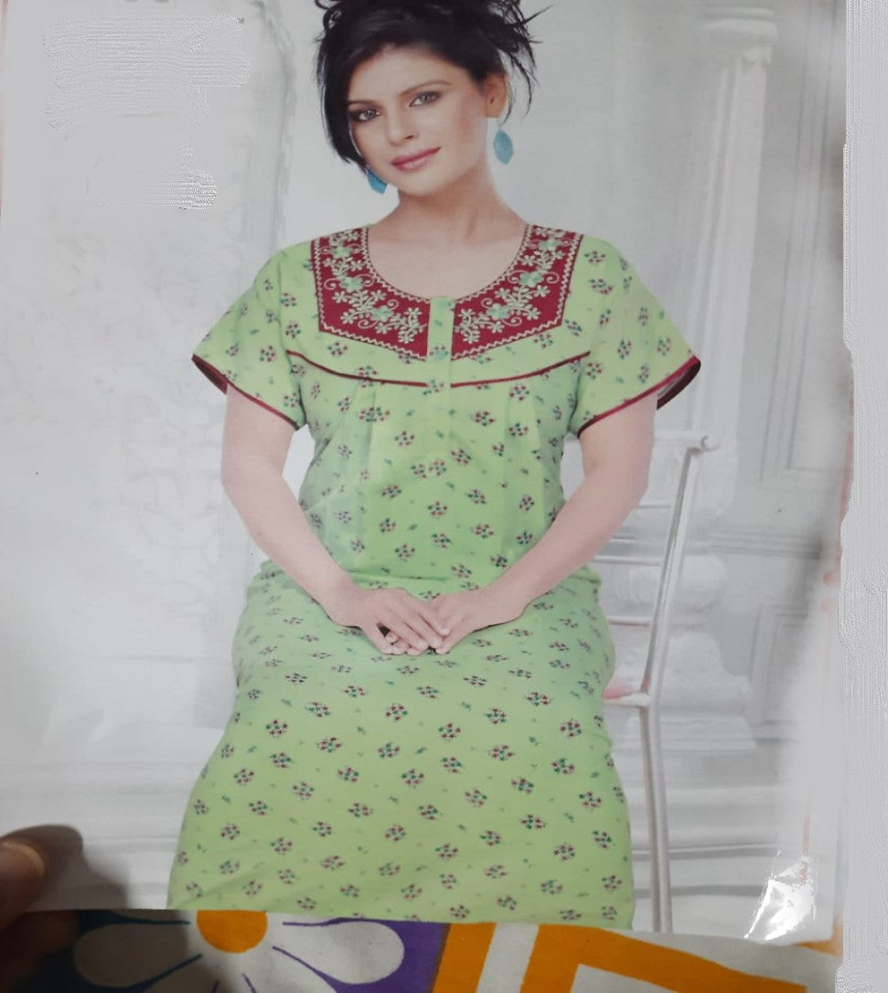 A woman wearing a green nighty with a floral pattern and a red border, featuring a pocket and a collar with button details.