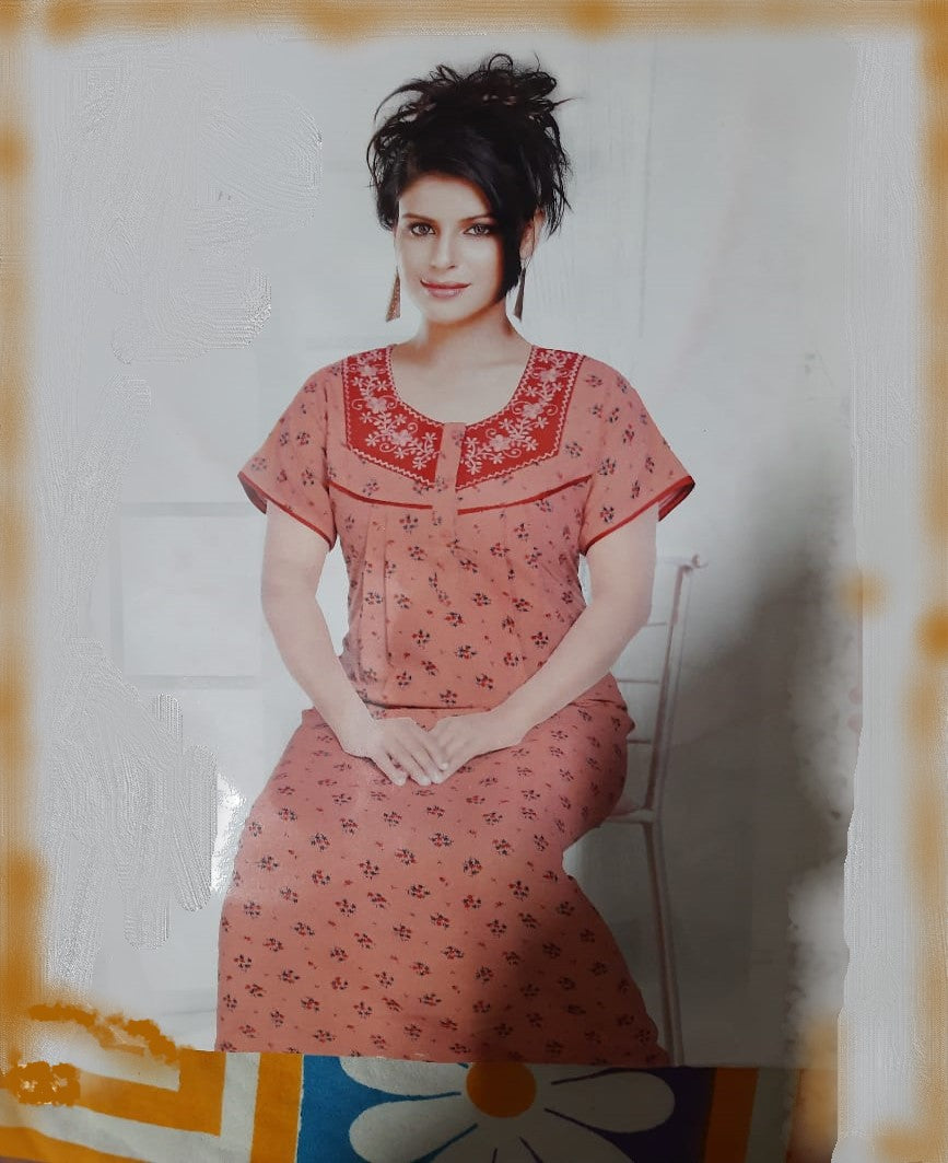 Woman wearing a red patterned outfit sitting on a chair against a white wall.